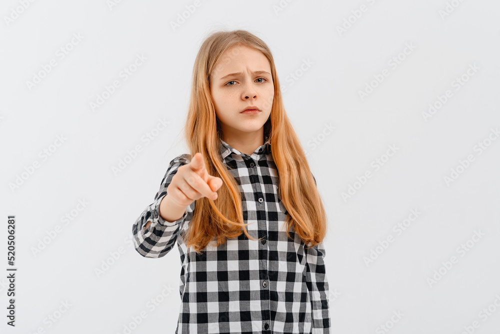 Portrait of serious teen girl wearing in casual shirt point index fingers camera, looks concerned, standing over white background Portrait of serious teen girl wearing in casual shirt point index fingers camera, looks concerned, standing over white background