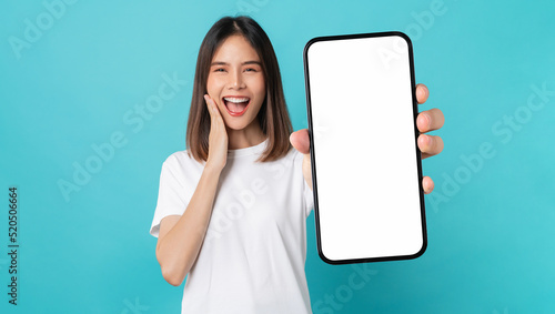 Studio shot of Beautiful Asian woman holding smartphone mockup of blank screen and smiling on blue background. © sitthiphong