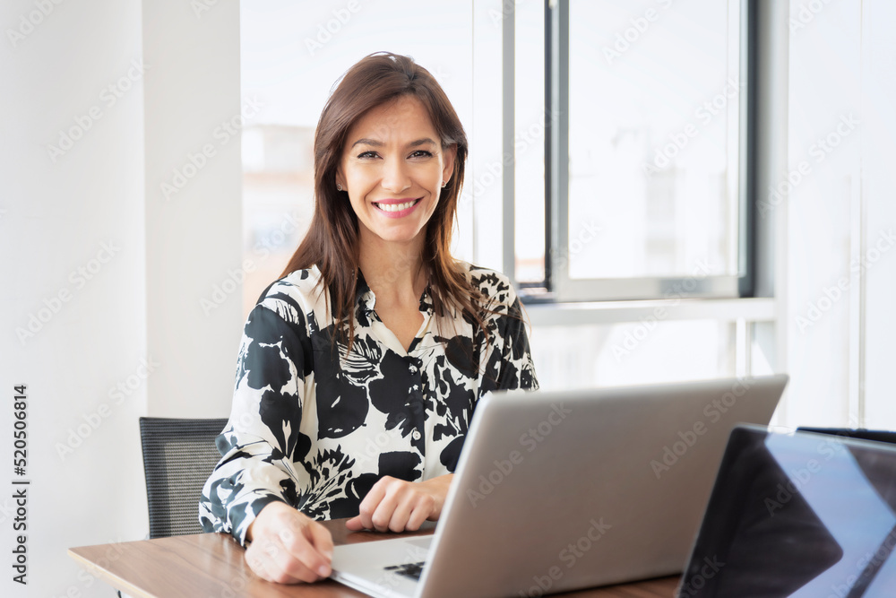 Confident middle aged businesswoman using laptop while working at the office Confident middle aged businesswoman using laptop while working at the office