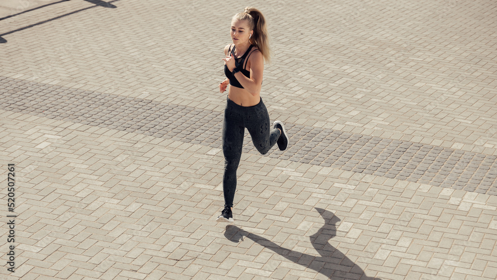 Athletic caucasian female jogger running on street