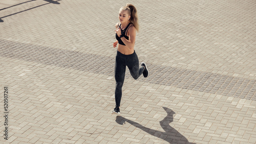 Athletic caucasian female jogger running on street