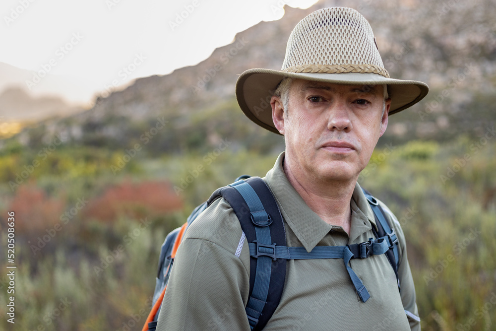 Portrait of male traveler wearing hat hiking at countryside
