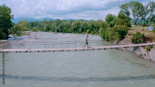 Man Walking on the Suspension Bridge in Tangkahan, North Sumatra, Indonesia photo