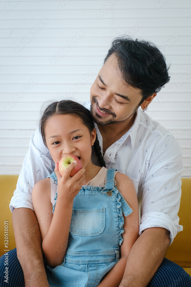 Asian happy family. Father sees his daughter eating apples and is very happy. Asian happy family. Father sees his daughter eating apples and is very happy.