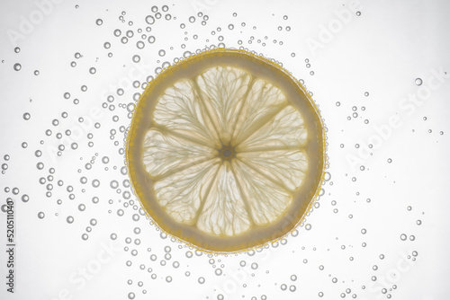 Fresh lemon slice in water with bubbles on white background