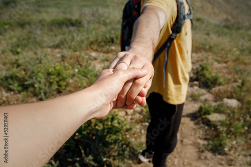 Hand of woman holding boyfriend and hiking on grassy land