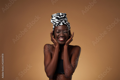 Fototapeta Front of pleased black girl wearing african turban