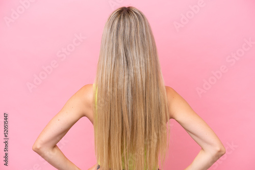Pretty blonde woman isolated on pink background in back position