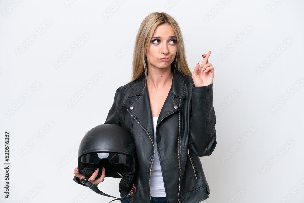 Pretty blonde woman with a motorcycle helmet isolated on white background with fingers crossing and wishing the best Pretty blonde woman with a motorcycle helmet isolated on white background with fingers crossing and wishing the best