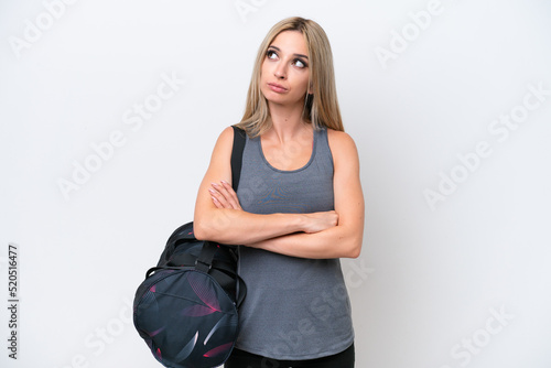 Young sport woman with sport bag isolated on white background looking up while smiling