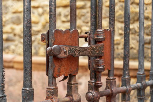 Ancient metal rusty wrought handle deadbolt (latch) of closed door of the lattice gate