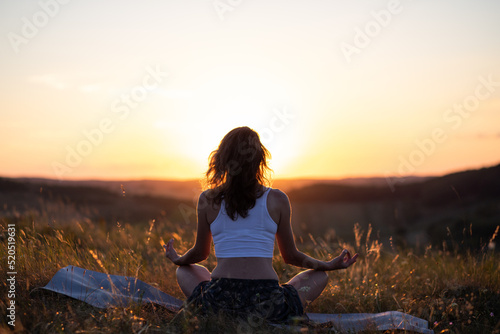 woman meditating outdoors at sunset
