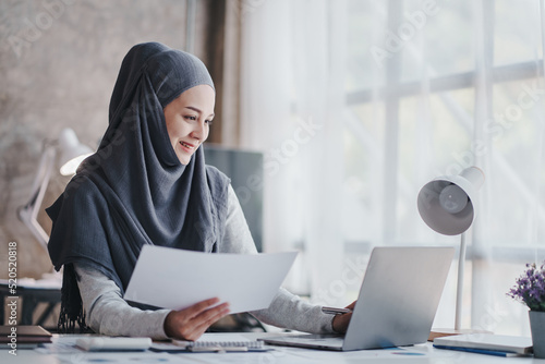 happy muslim business women in hijab at work smiling arab woman taking notes and work on laptop
