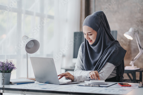 happy muslim business women in hijab at work smiling arab woman taking notes and work on laptop