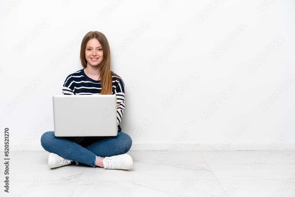 Young caucasian woman with a laptop sitting on the floor isolated on white background keeping the arms crossed in frontal position Young caucasian woman with a laptop sitting on the floor isolated on white background keeping the arms crossed in frontal position