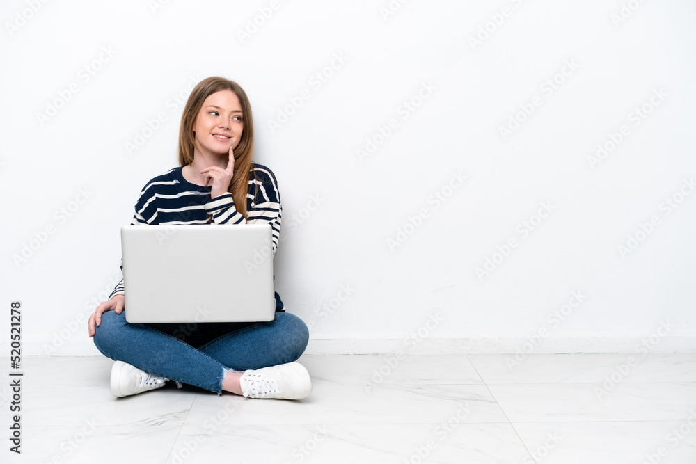 Young caucasian woman with a laptop sitting on the floor isolated on white background thinking an idea while looking up Young caucasian woman with a laptop sitting on the floor isolated on white background thinking an idea while looking up