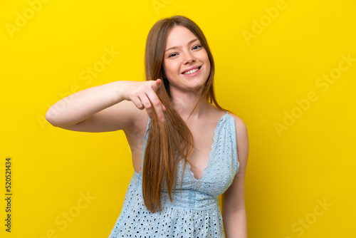 Young caucasian woman isolated on yellow background pointing front with happy expression
