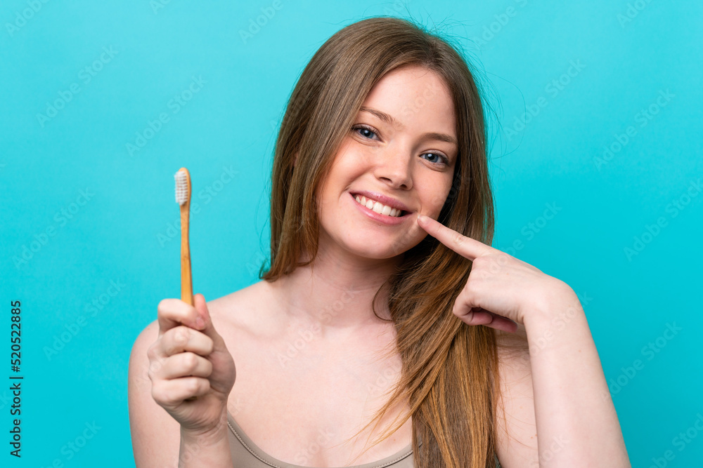 Young caucasian woman isolated on blue background with a toothbrush and happy expression Young caucasian woman isolated on blue background with a toothbrush and happy expression