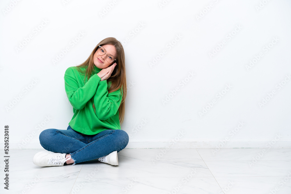 Young caucasian woman sitting on the floor isolated on white background making sleep gesture in dorable expression Young caucasian woman sitting on the floor isolated on white background making sleep gesture in dorable expression