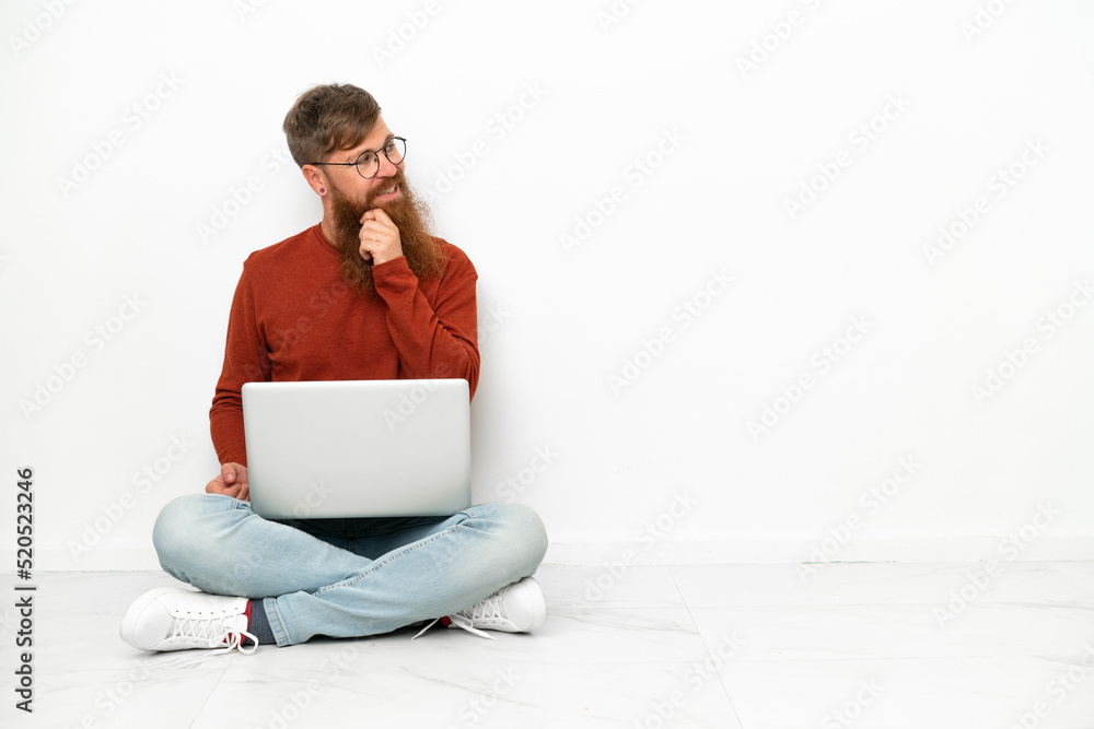 Young reddish caucasian man with laptop isolated on white background looking to the side and smiling Young reddish caucasian man with laptop isolated on white background looking to the side and smiling