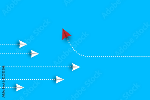 Group of white paper plane in one direction and one red paper plane pointing in different way on blue background.