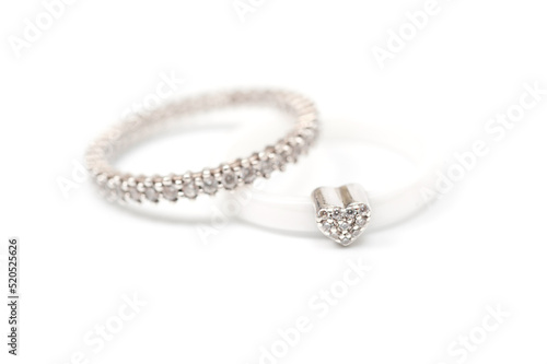 A white ceramic ring with a metal heart decorated with rhinestones and a silver ring with decorative stones.