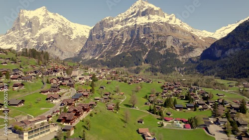 Aerial drone footage raising down and pushing out of Grindelwald village, with train and bus departing photo