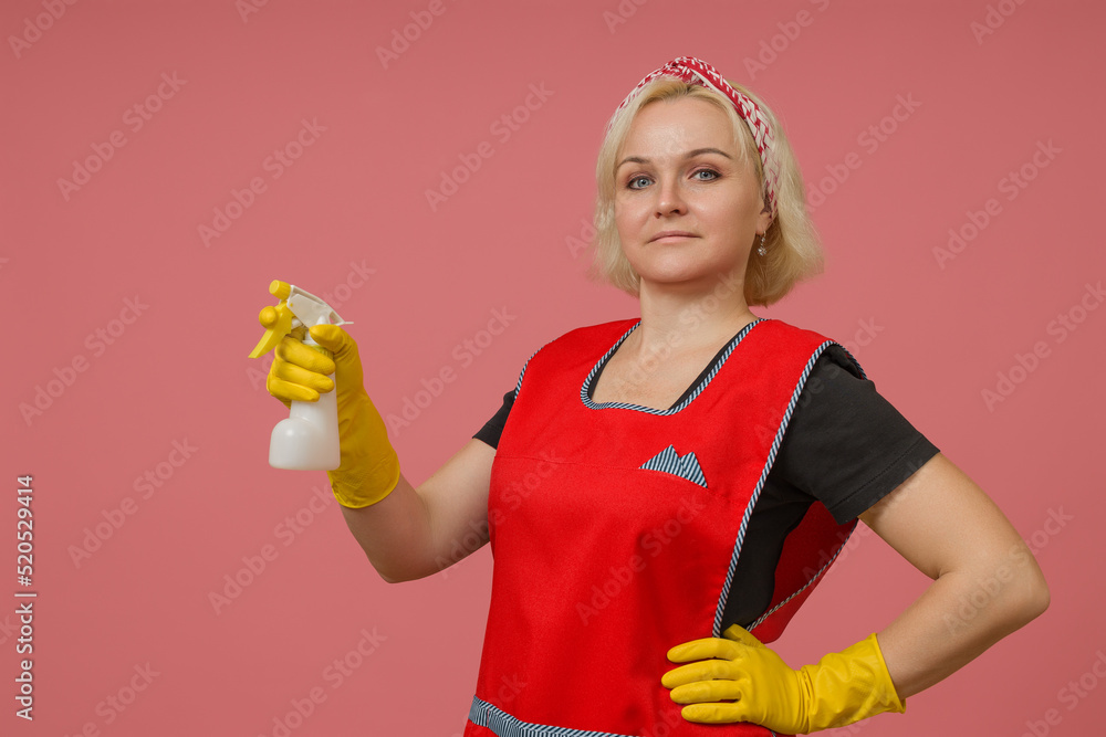 woman cleaner in an apron and gloves with a sprayer in her hands on a colored background woman cleaner in an apron and gloves with a sprayer in her hands on a colored background
