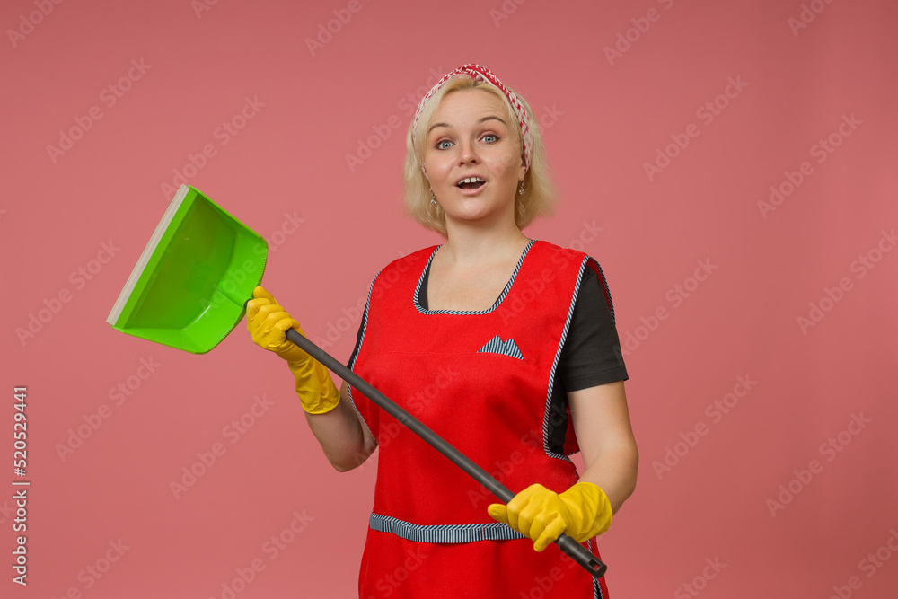 cleaning lady in an apron and gloves with a dustpan in her hands on a ...