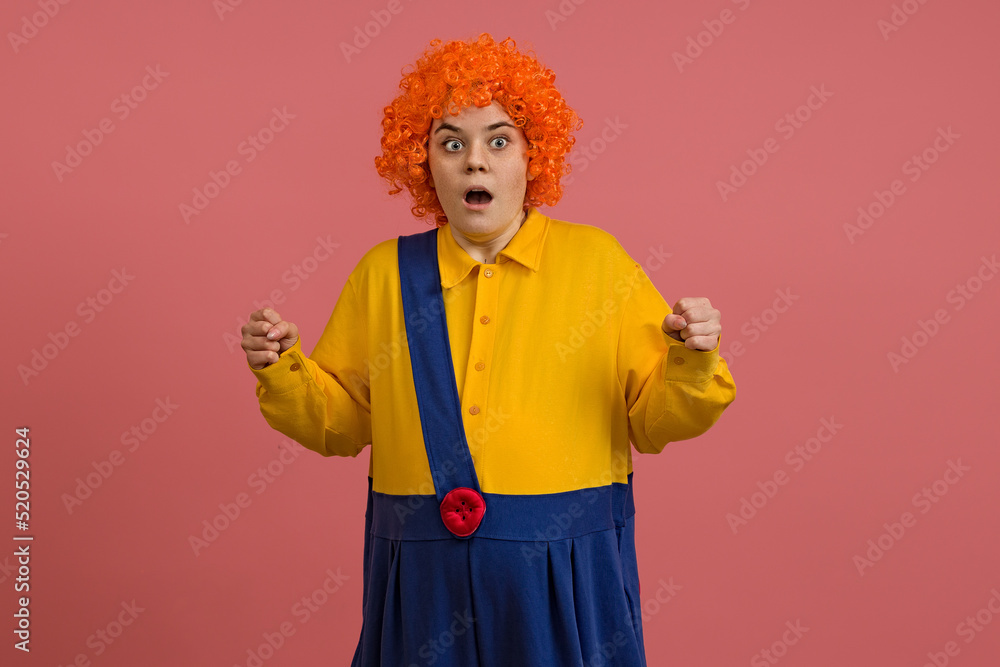 shocked girl in a clown costume and a bright wig on a colored background shocked girl in a clown costume and a bright wig on a colored background