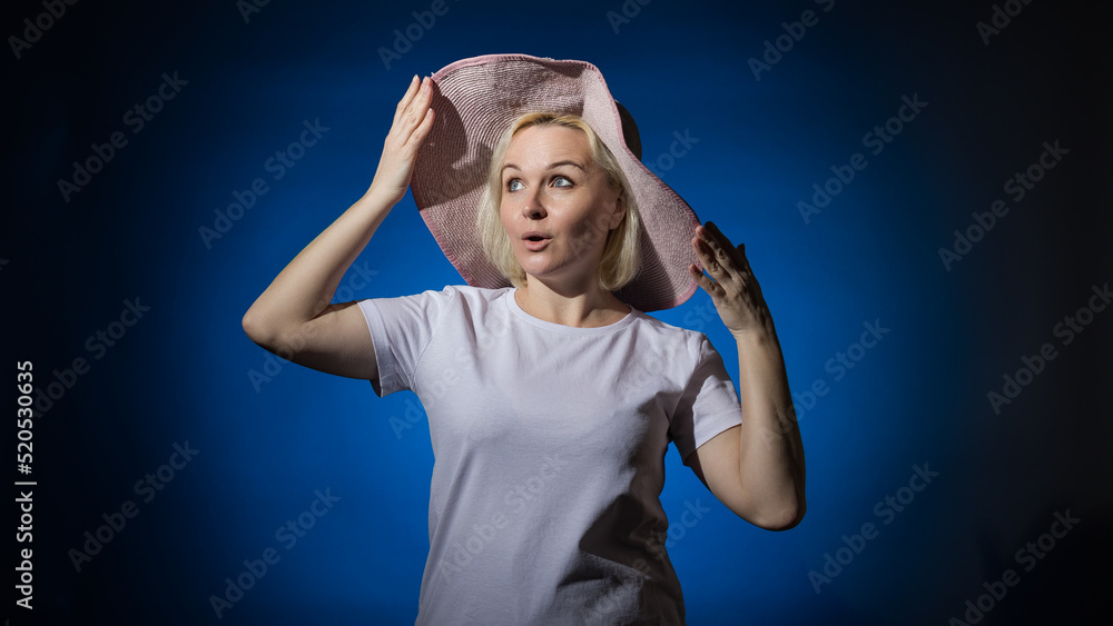 Cheerful woman in a white t-shirt and hat on a blue background. Cheerful woman in a white t-shirt and hat on a blue background.