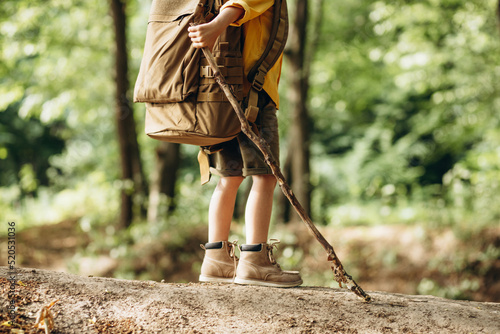 Boy traveler walking in the forest with rucksuck and stick photo