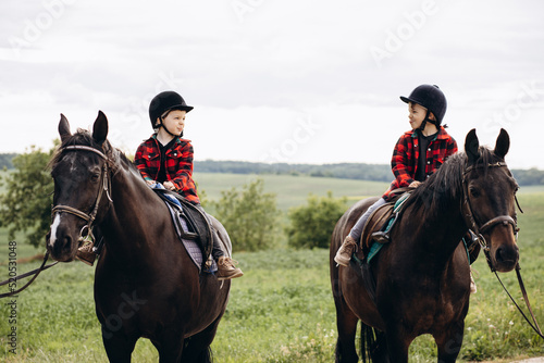 Two boys brothers riding horses