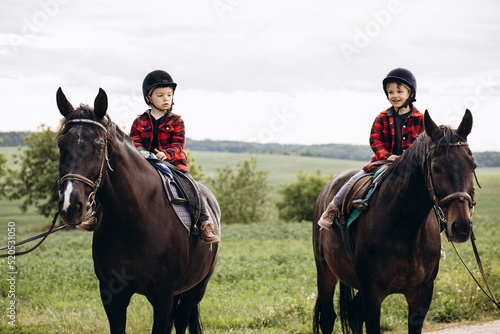 Two boys brothers riding horses