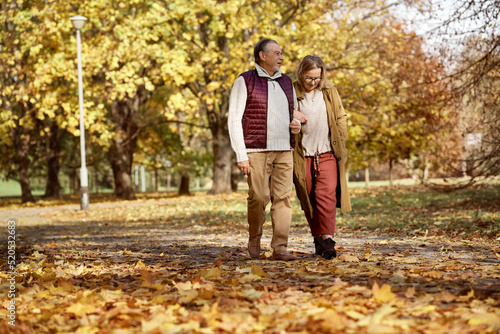 Senior woman and man walking together at the park during the autumn