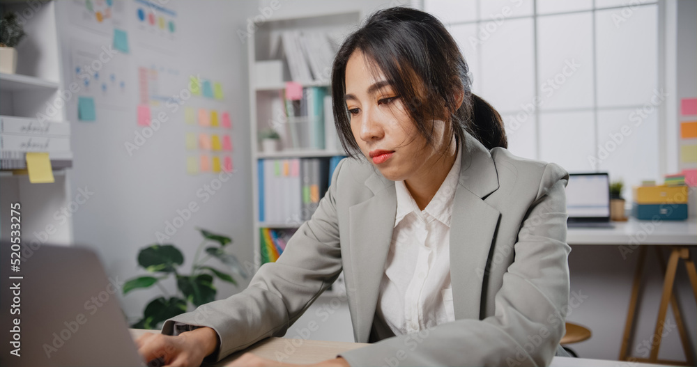 Young Asian businesswoman sit on desk with laptop overworked tired burnout syndrome at office. Exhausted lady with sleeply eye at workplace, Girl not enjoy unhappy with work, Work mental health. Young Asian businesswoman sit on desk with laptop overworked tired burnout syndrome at office. Exhausted lady with sleeply eye at workplace, Girl not enjoy unhappy with work, Work mental health.