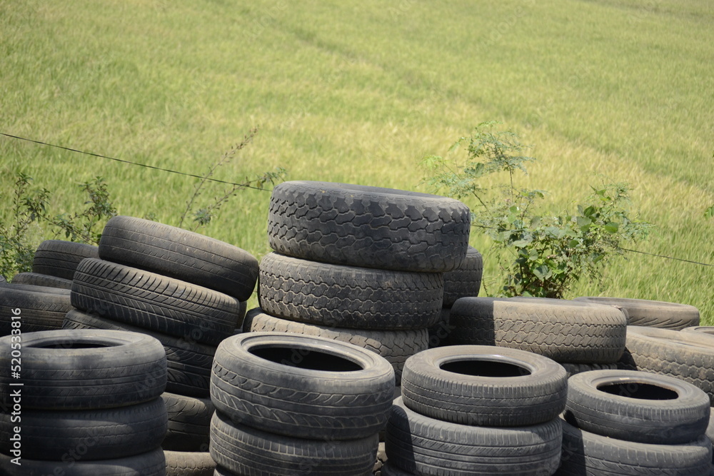 pile of used tires near the rice fields. The used tires have various sizes pile of used tires near the rice fields. The used tires have various sizes