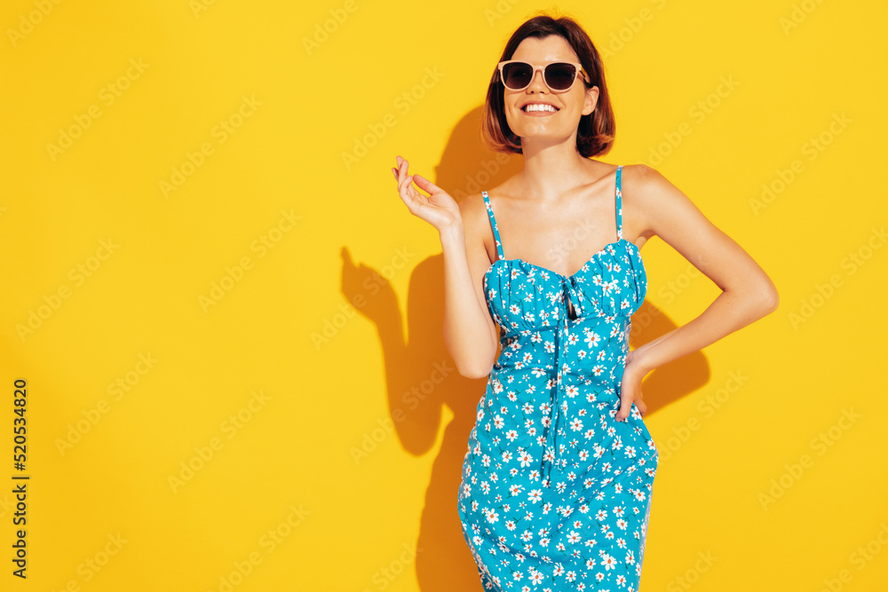 Portrait of young beautiful smiling female in trendy summer dress. Sexy carefree woman posing near yellow wall in studio. Positive model having fun and going crazy. Cheerful and happy. In sunglasses Portrait of young beautiful smiling female in trendy summer dress. Sexy carefree woman posing near yellow wall in studio. Positive model having fun and going crazy. Cheerful and happy. In sunglasses