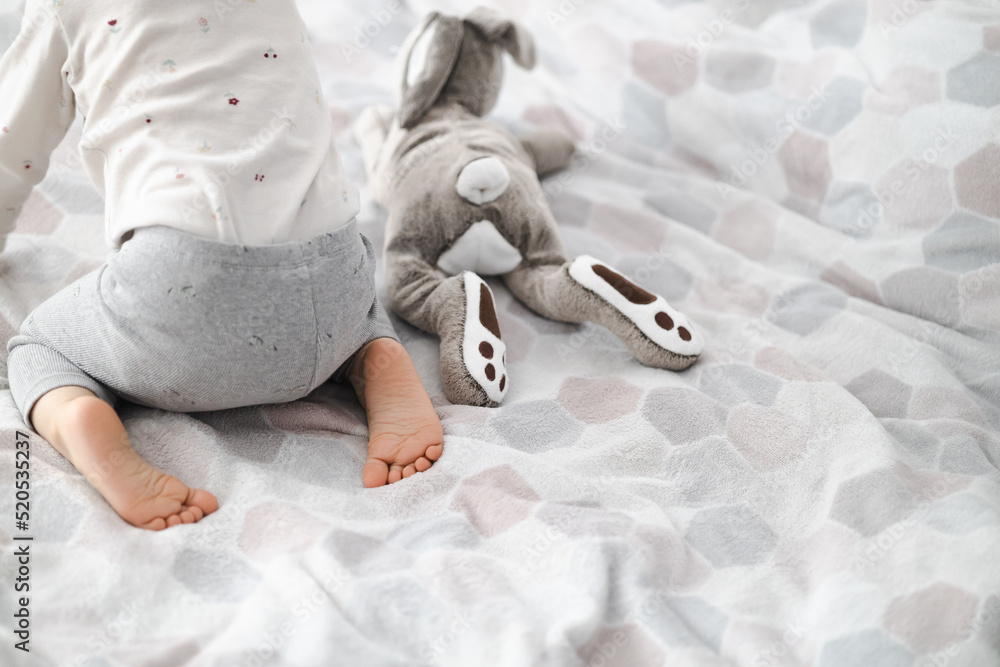toddler girl little feet with toy rabbit - obrazy, fototapety, plakaty 