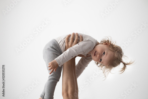 mother holds her daughter in her hands, toddler girl holds up