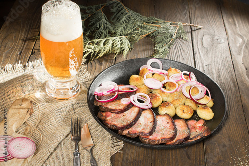 lunch of fried ham with potatoes and onions in a pan next to a glass of beer photo