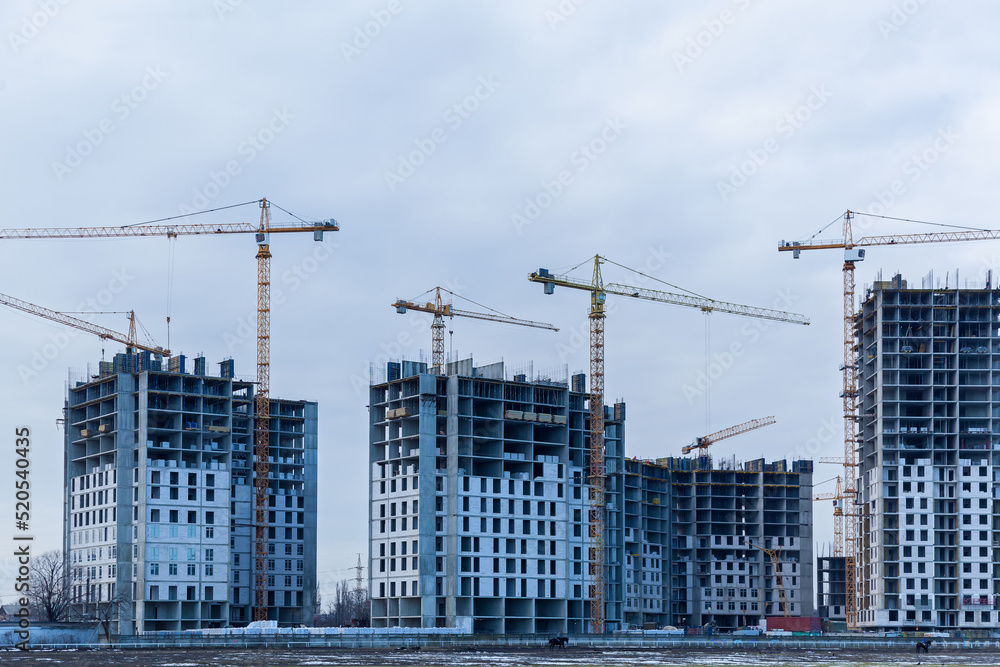 Construction site of multi-storey houses and building cranes Construction site of multi-storey houses and building cranes