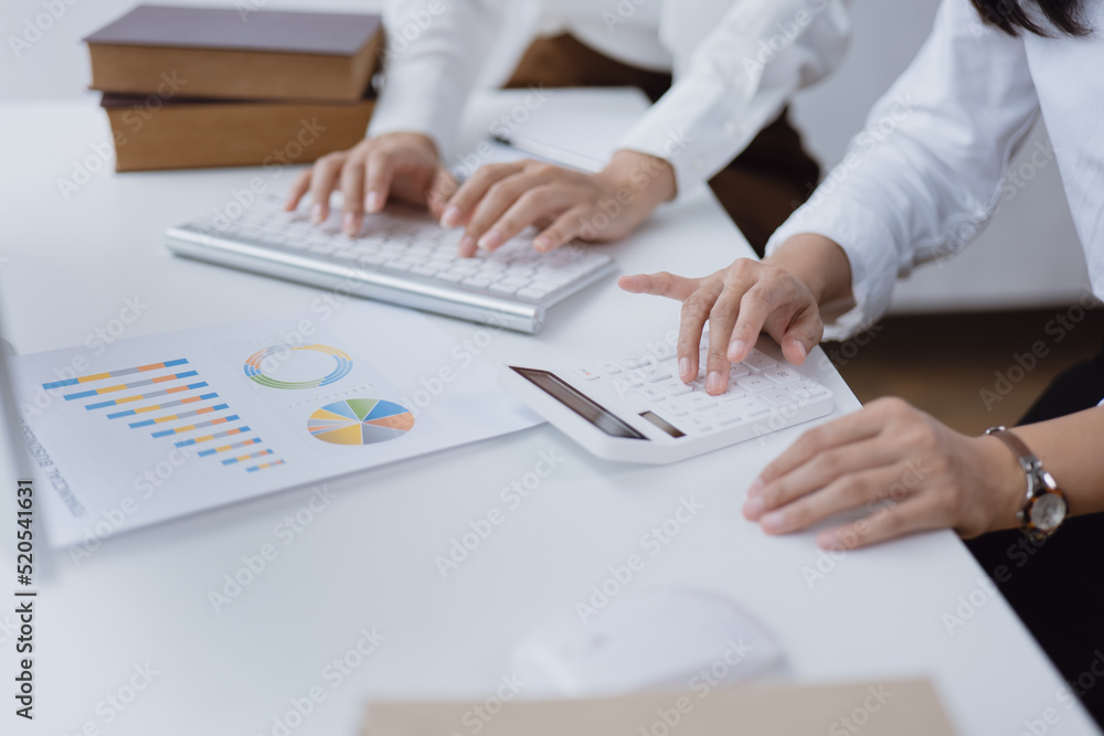 Business women are discussed on paperwork that show accounting numbers tables and working on laptop in office space. Business women are discussed on paperwork that show accounting numbers tables and working on laptop in office space.