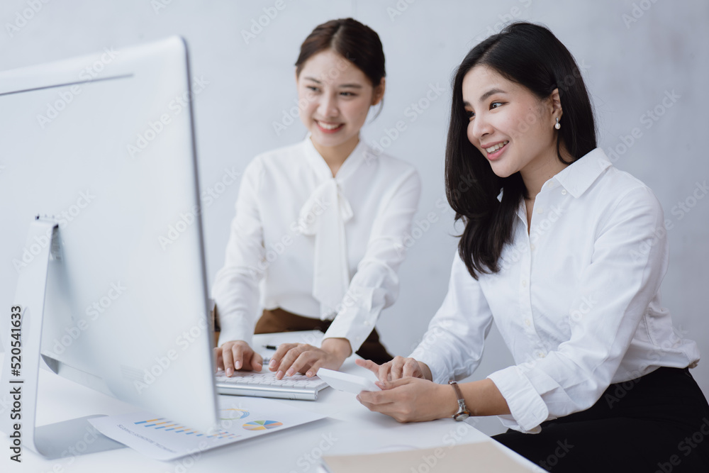 Business women are discussed on paperwork that show accounting numbers tables and working on laptop in office space. Business women are discussed on paperwork that show accounting numbers tables and working on laptop in office space.