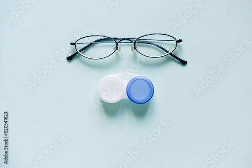 Glasses and a case for contact lenses on a blue background. concept of choosing a method of vision correction. copy space