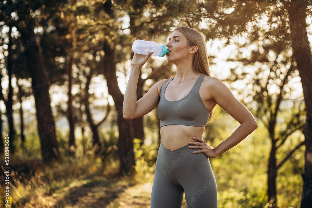 Fit woman in sportswear drinking water in park Fit woman in sportswear drinking water in park