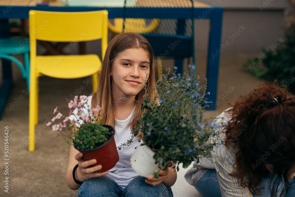 portrait of teenager girl holding houseplant and looking at camera