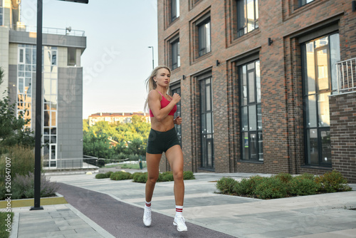 A young sportswoman is engaged in sports in the city. The girl runs around in the morning