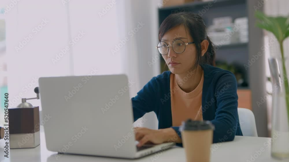 Young Asian woman drinks coffee closing eyes in pleasure sits in front of laptop located at home. Freelance, lifestyle. Young Asian woman drinks coffee closing eyes in pleasure sits in front of laptop located at home. Freelance, lifestyle.