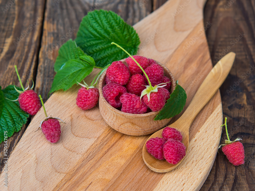 harvested red raspberries, large red garden raspberries in a wooden bowl on a wooden table harvested red raspberries, large red garden raspberries in a wooden bowl on a wooden table